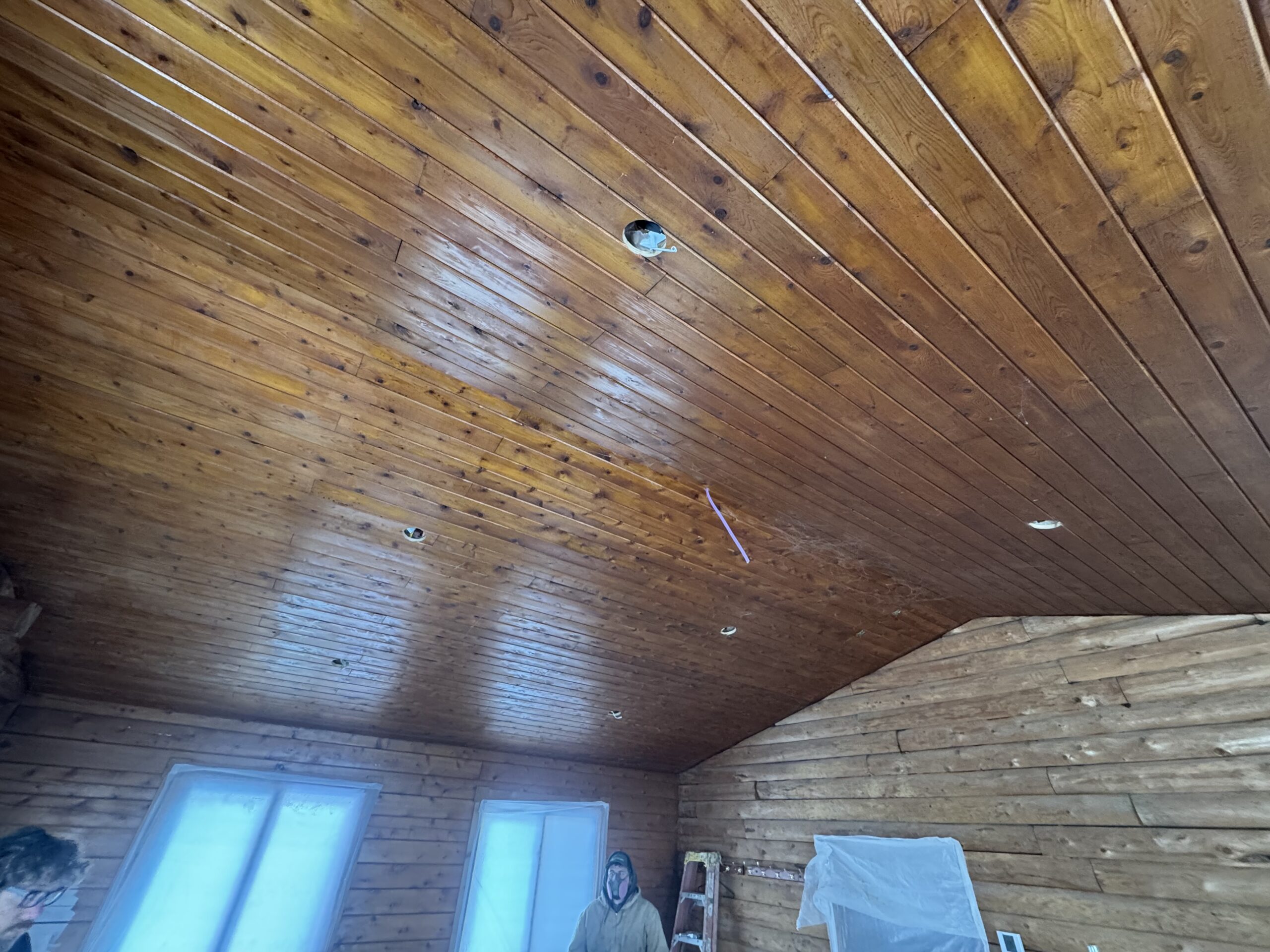 Log Cabin Bedroom Ceiling and Wall Sandblasting Log cabin bedroom ceiling and log wall being sandblasted during renovation by Green Mountain Mobile Sandblasting and Powder Coating LLC