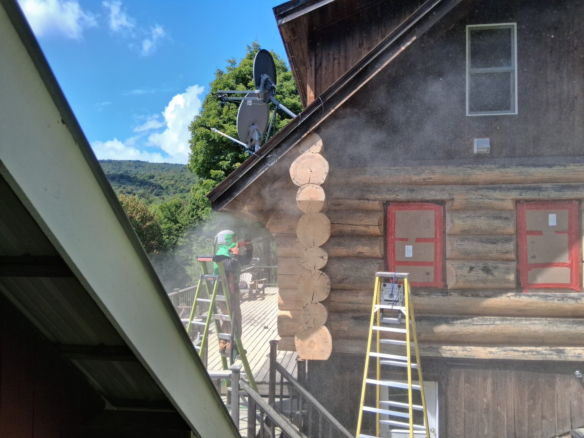 Log Cabin Sandblasting & Weathering Removal – Roxbury, Vermont Before and after log cabin restoration in Roxbury Vermont showing gray weathered logs sandblasted back to clean natural wood
