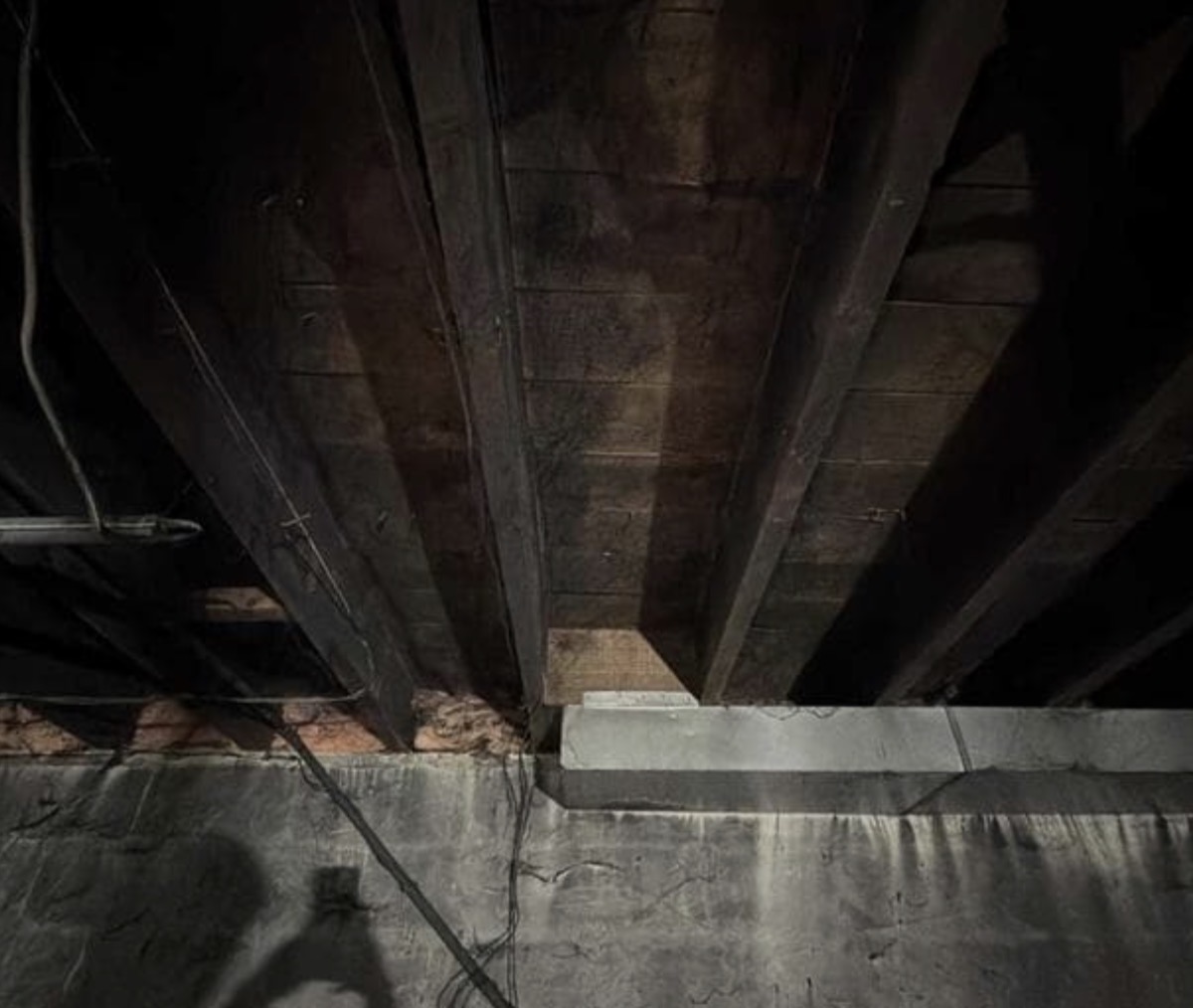 Fire Damage Sandblasting – Bristol, Vermont Before and after fire damage restoration in Bristol Vermont showing sandblasted wood floor joists and concrete basement walls