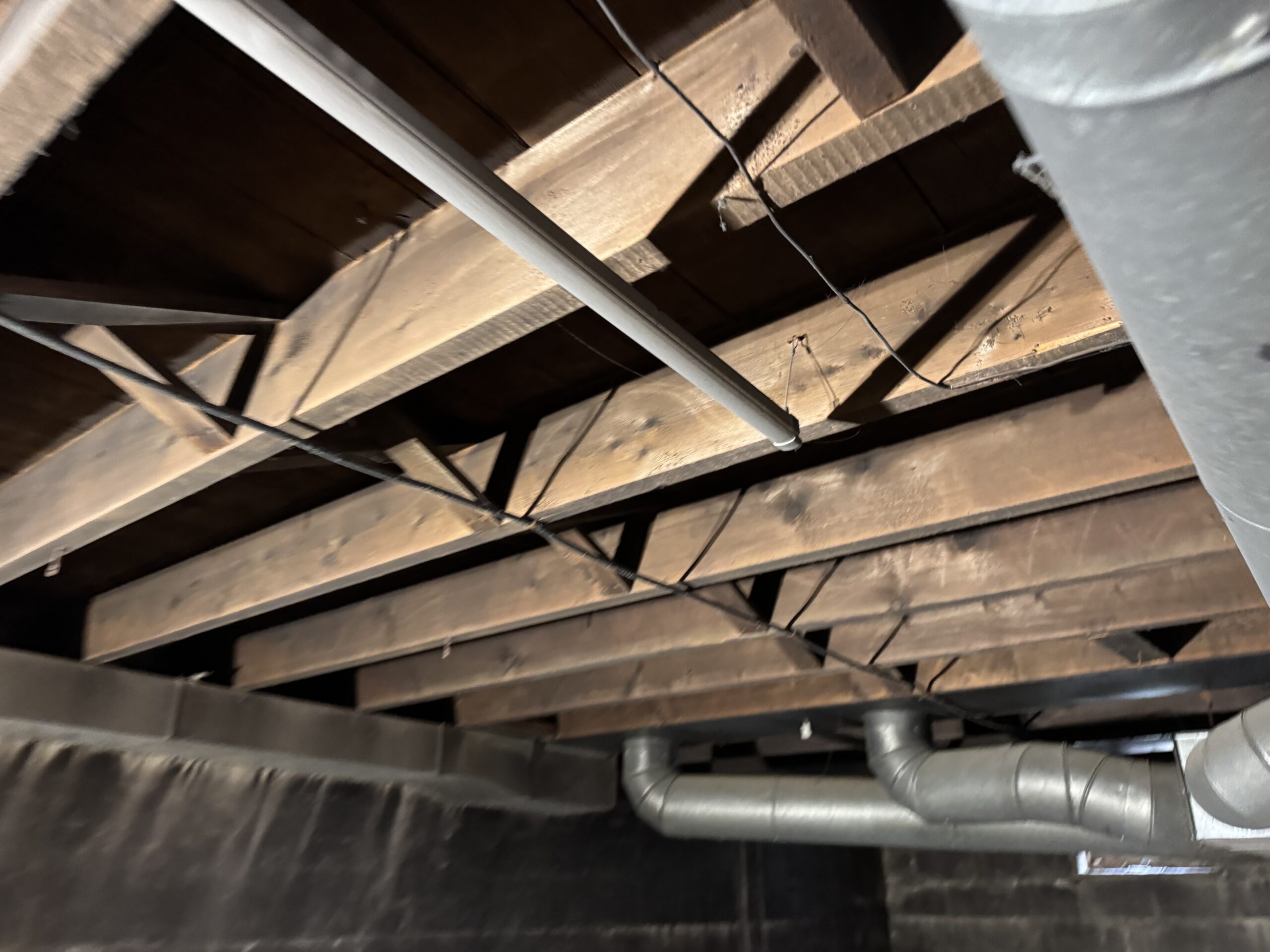 Fire Damage Sandblasting – Bristol, Vermont Before and after fire damage restoration in Bristol Vermont showing sandblasted wood floor joists and concrete basement walls