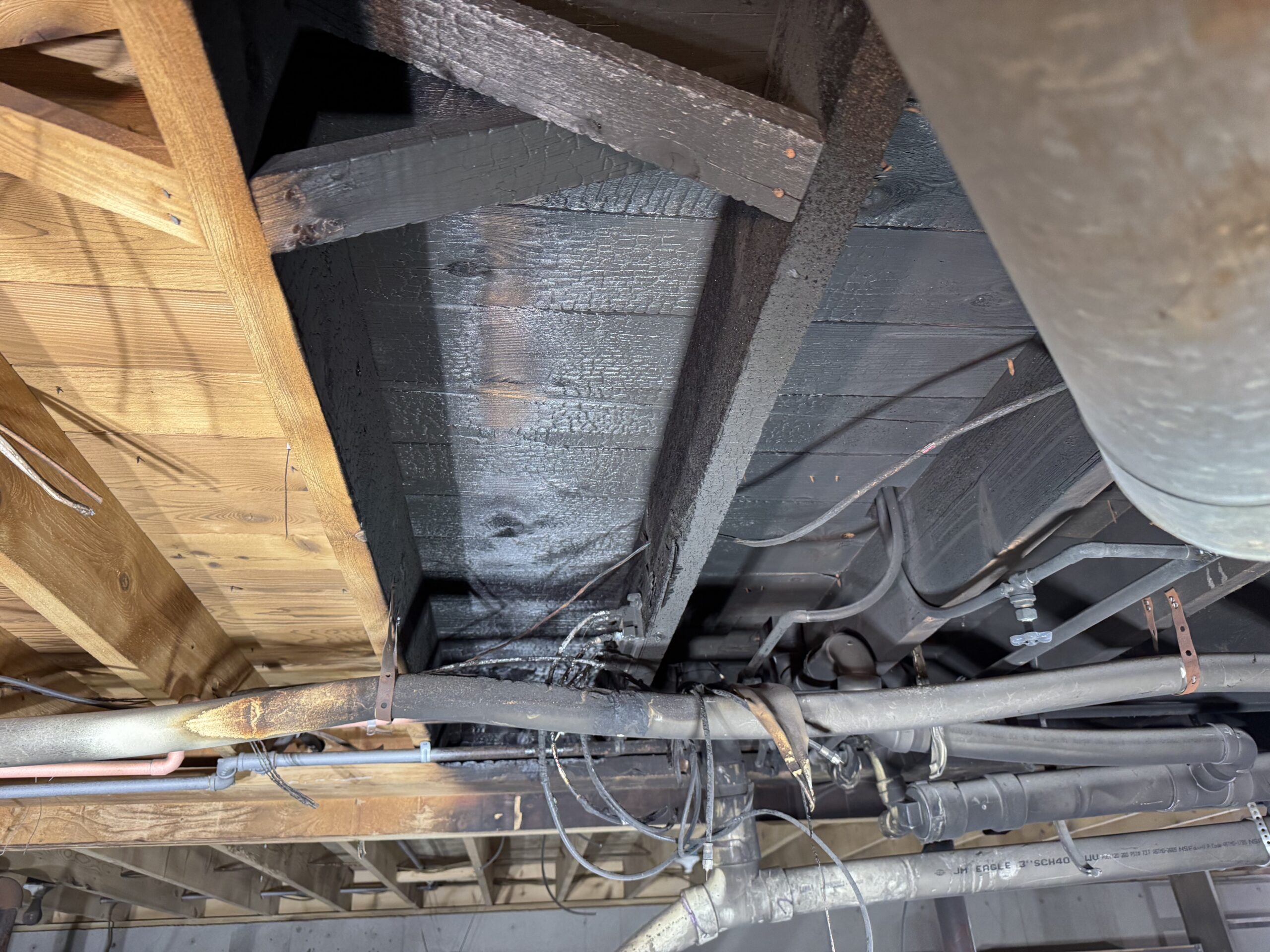 Fire Damage Sandblasting – Bristol, Vermont Before and after fire damage restoration in Bristol Vermont showing sandblasted wood floor joists and concrete basement walls