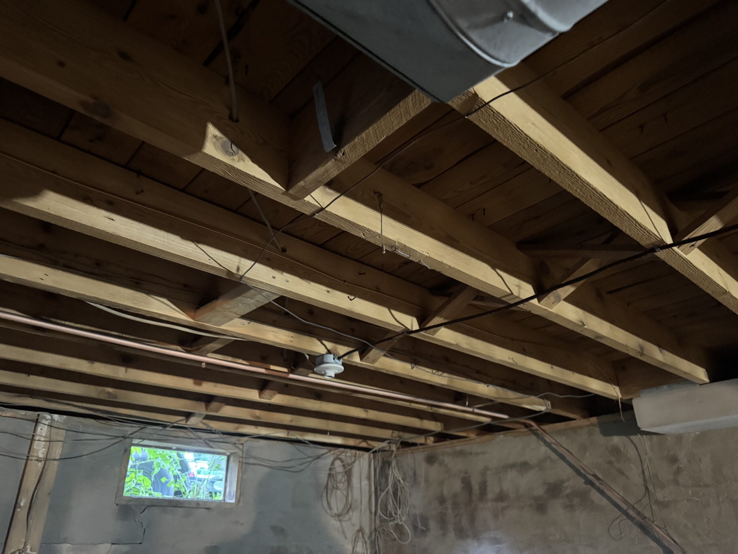 Fire Damage Sandblasting – Bristol, Vermont Before and after fire damage restoration in Bristol Vermont showing sandblasted wood floor joists and concrete basement walls