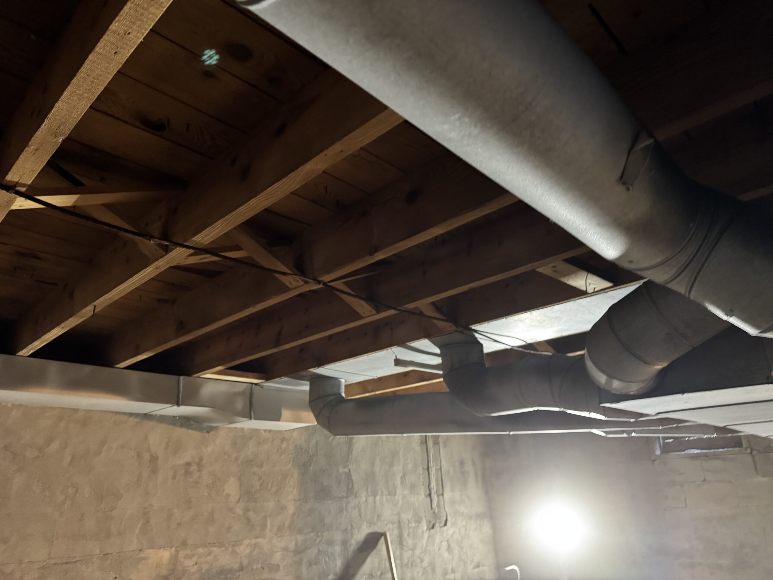 Fire Damage Sandblasting – Bristol, Vermont Before and after fire damage restoration in Bristol Vermont showing sandblasted wood floor joists and concrete basement walls