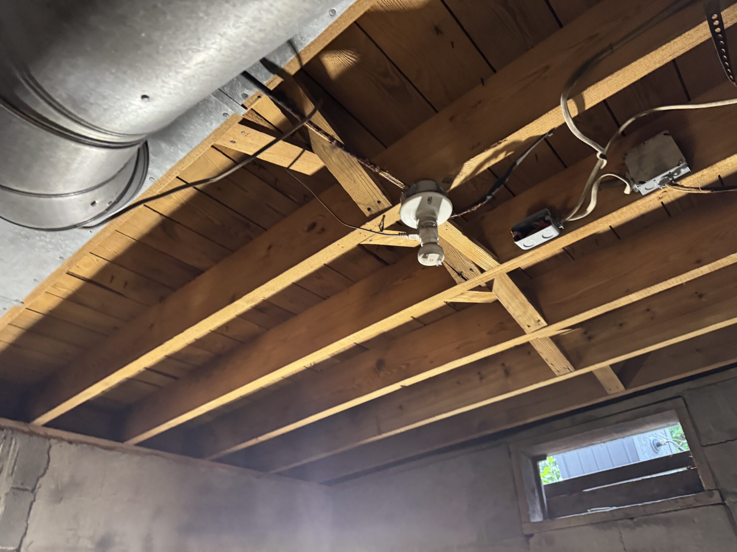 Fire Damage Sandblasting – Bristol, Vermont Before and after fire damage restoration in Bristol Vermont showing sandblasted wood floor joists and concrete basement walls