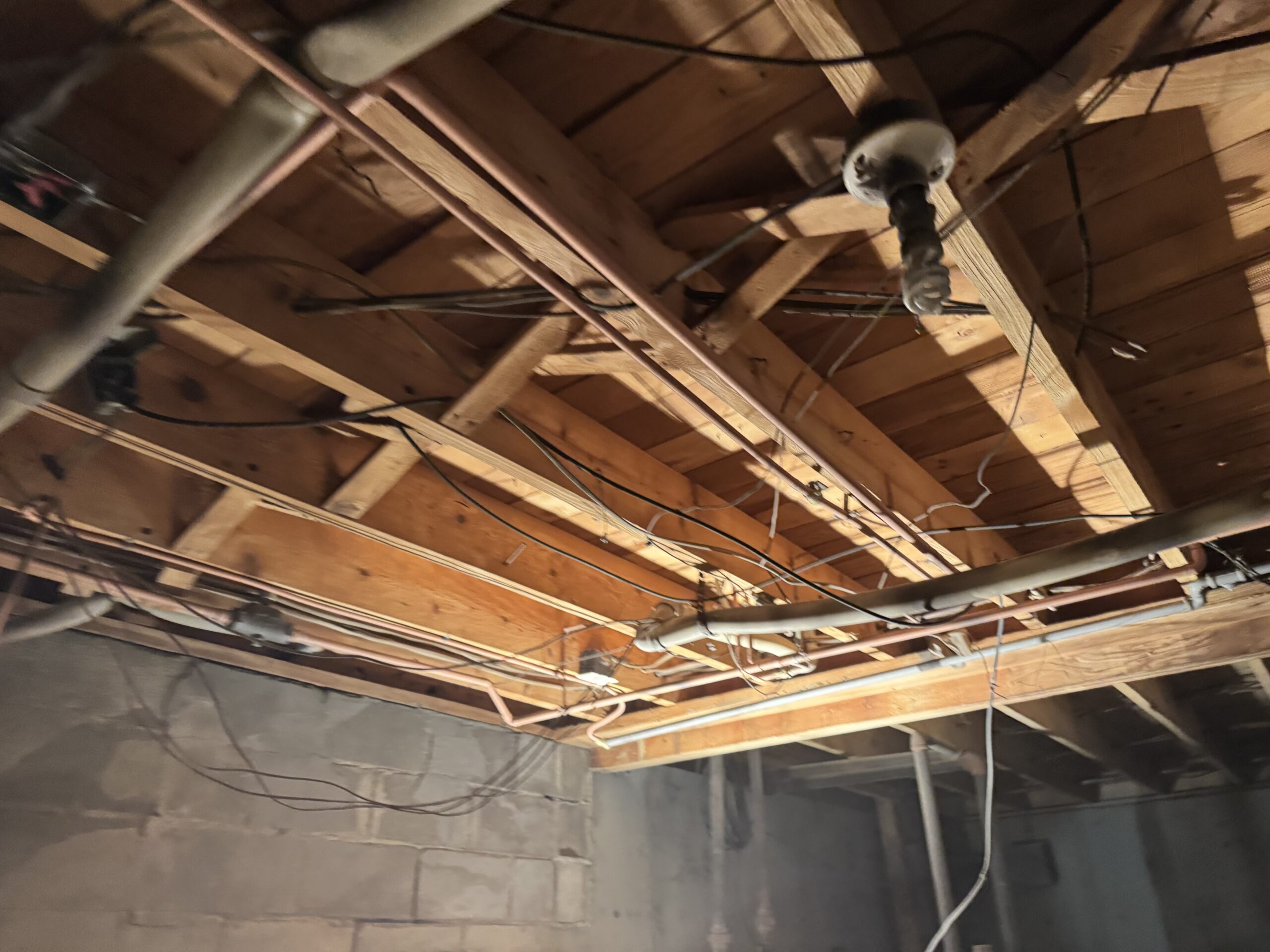 Fire Damage Sandblasting – Bristol, Vermont Before and after fire damage restoration in Bristol Vermont showing sandblasted wood floor joists and concrete basement walls