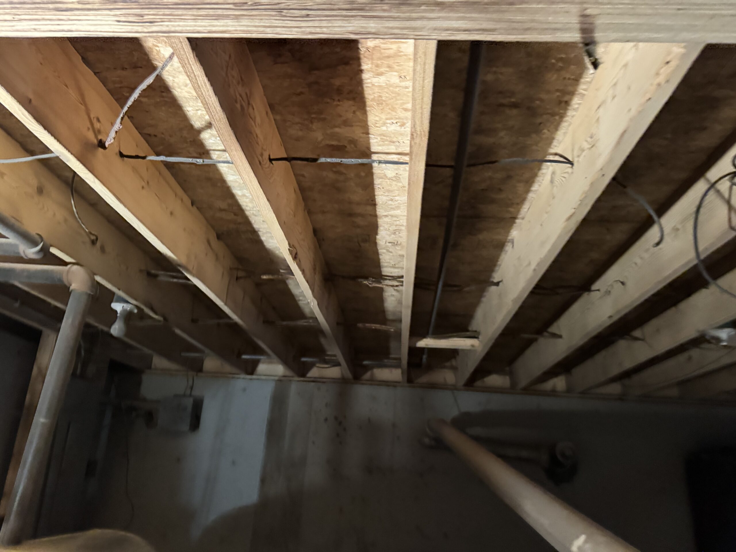 Fire Damage Sandblasting – Bristol, Vermont Before and after fire damage restoration in Bristol Vermont showing sandblasted wood floor joists and concrete basement walls