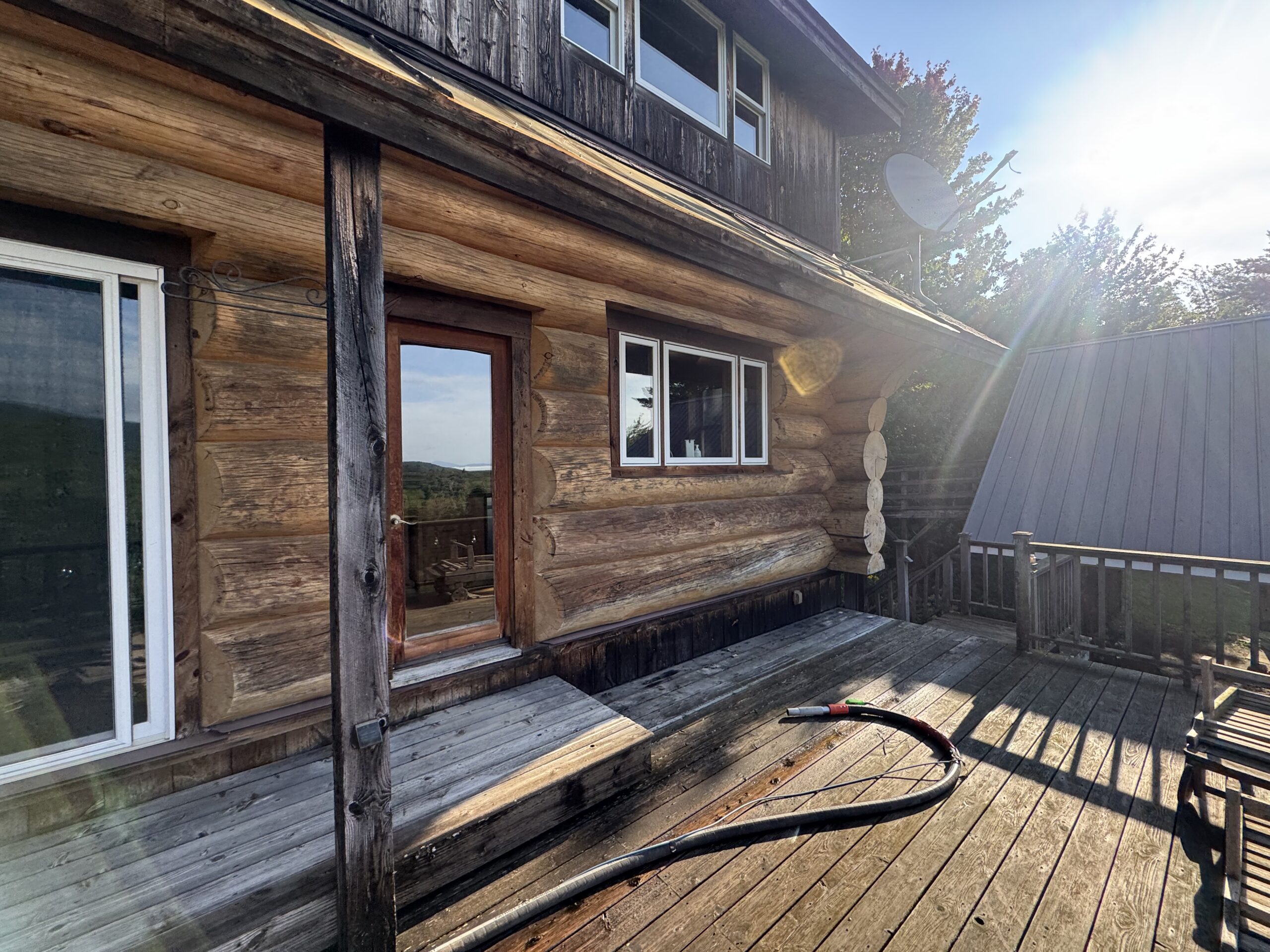 Log Cabin Sandblasting & Weathering Removal – Roxbury, Vermont Before and after log cabin restoration in Roxbury Vermont showing gray weathered logs sandblasted back to clean natural wood