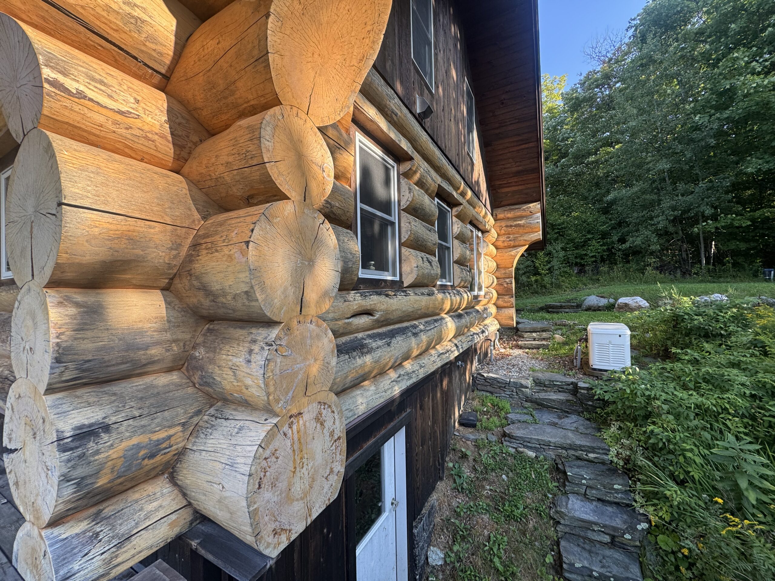 Log Cabin Sandblasting & Weathering Removal – Roxbury, Vermont Before and after log cabin restoration in Roxbury Vermont showing gray weathered logs sandblasted back to clean natural wood