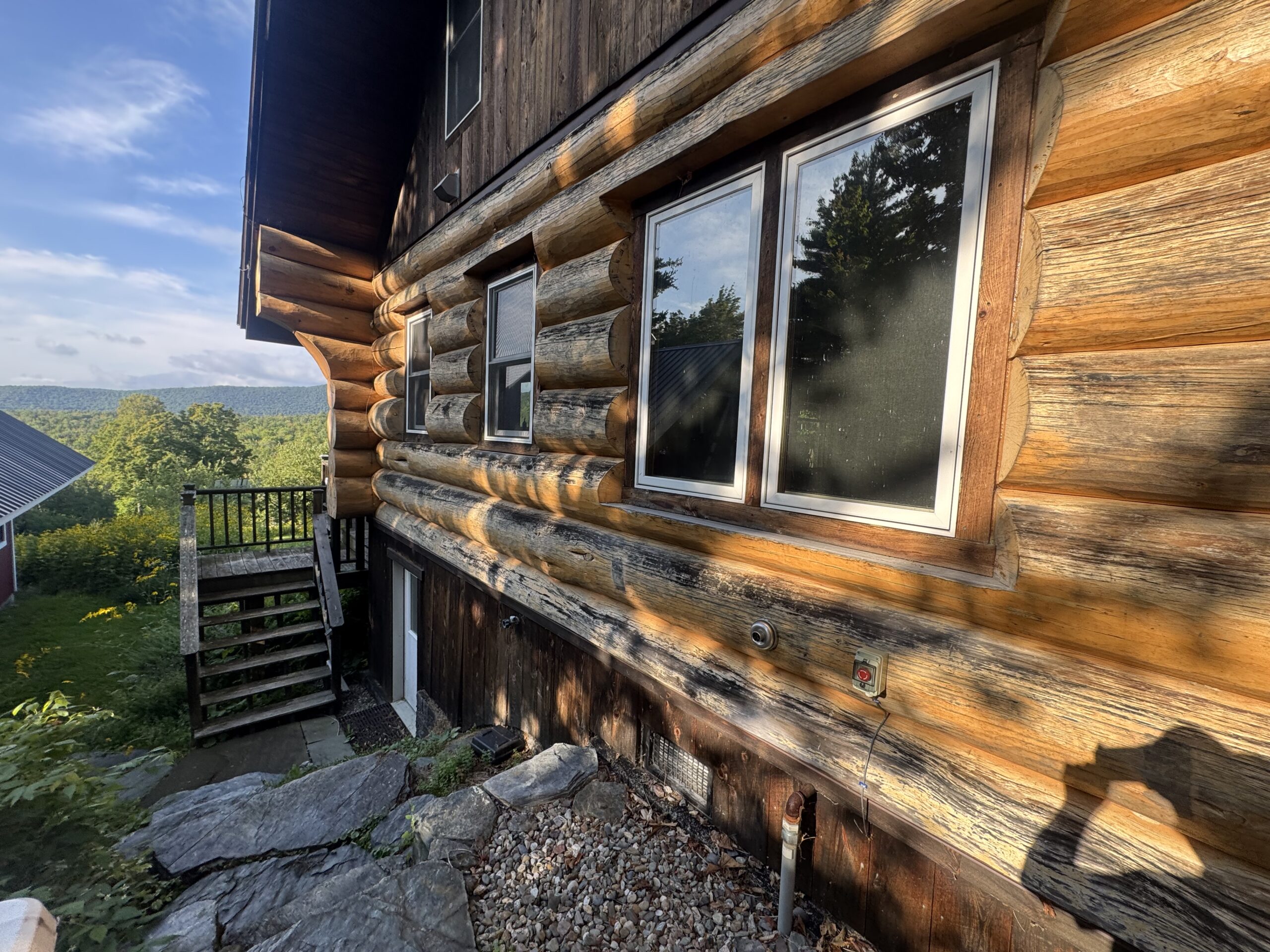 Log Cabin Sandblasting & Weathering Removal – Roxbury, Vermont Before and after log cabin restoration in Roxbury Vermont showing gray weathered logs sandblasted back to clean natural wood