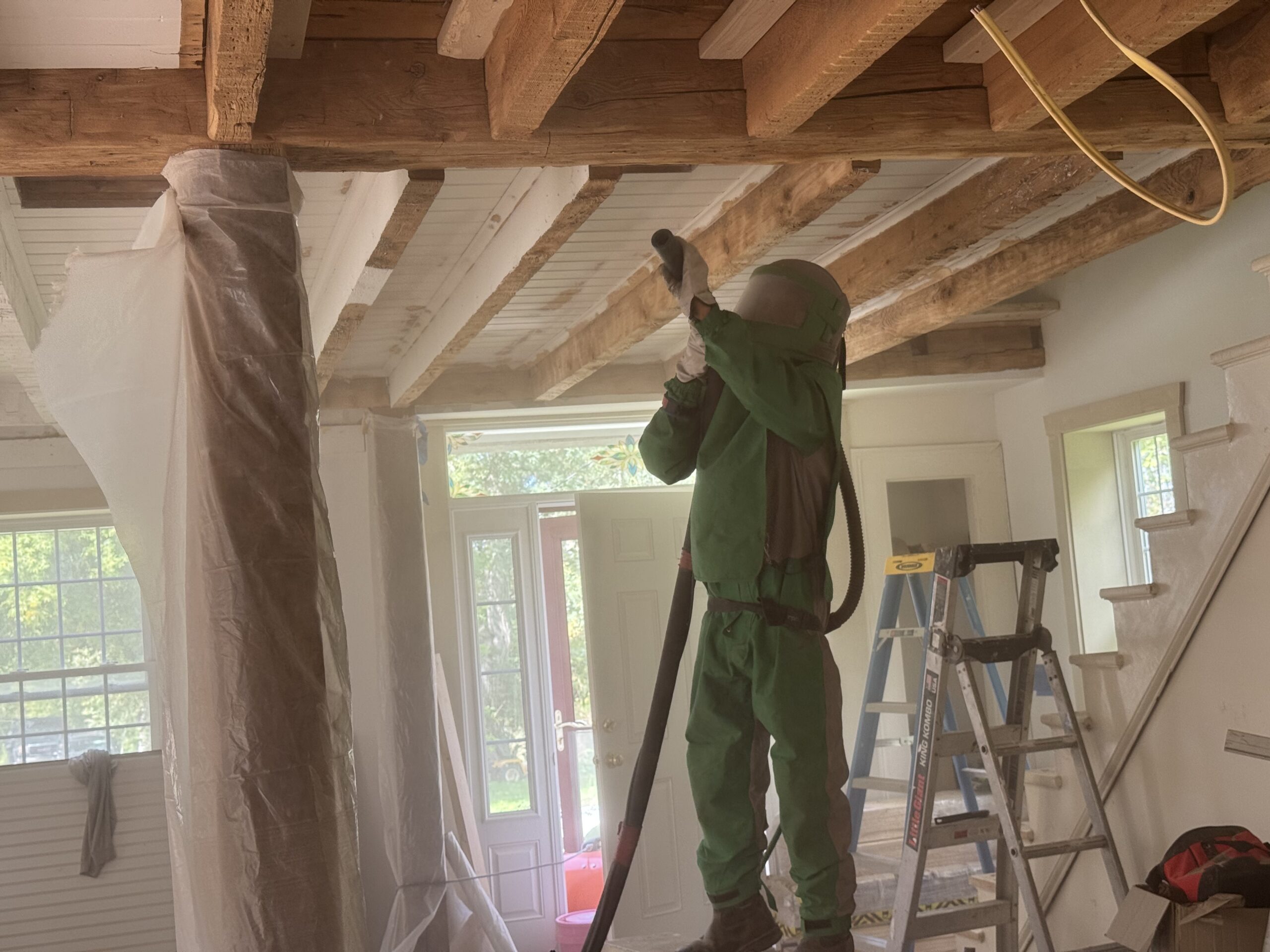 Interior Wood Beam Sandblasting – Isle La Motte, Vermont Interior ceiling beams in an Isle La Motte Vermont home selectively sandblasted to remove paint while leaving the surrounding wood untouched